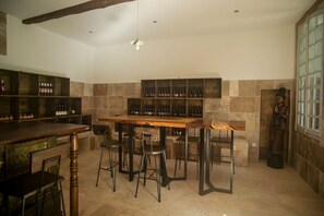Un espace bar avec des tabourets en bois, un comptoir et des étagÚres remplies de bouteilles.