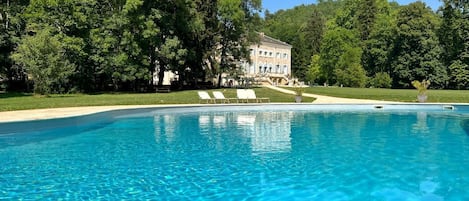 A clear swimming pool with a building in the background.