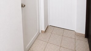 A hallway with two white doors, a light switch, and a tiled floor. - Beautiful 1-bedroom studio with AC in charming Arecibo (Arecibo)