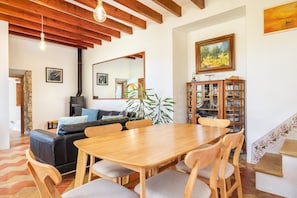 Un comedor con una mesa y sillas de madera, un sofá de cuero negro, un espejo grande y un aparador con cristalería.