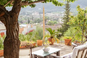 Una terraza con mesa, sillas, plantas en macetas y vistas a un pueblo.