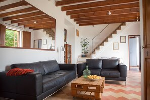 Una sala de estar con un sofá de cuero negro, una mesa de centro de madera y una escalera con vigas de madera.