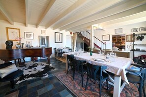 Un comedor con un piano, una mesa preparada para cuatro personas y una escalera que sube a otra habitación.