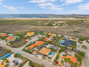 Ein Luftbild eines Küstenresorts mit mehreren Gebäuden, Swimmingpools und einem Strand im Hintergrund.