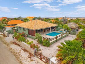 Ein Haus mit Schwimmbad, umgeben von viel Grün und blauem Himmel.