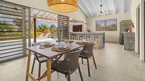 Une cuisine moderne dotée d’un coin bar, de grandes fenêtres et d’un espace repas avec une table et des chaises.