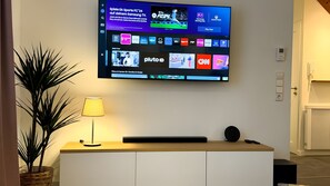 A flat-screen TV mounted on a wall displaying various channels and a game interface.