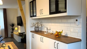 Een moderne keuken met witte kastjes, een houten aanrechtblad en een schaal met fruit.