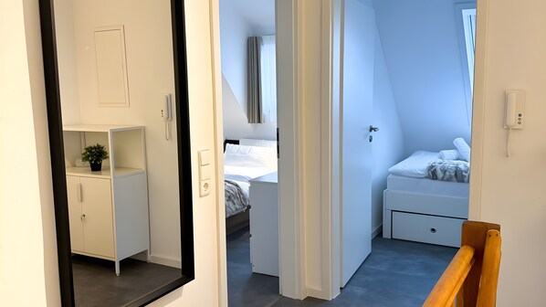 Una habitación de hotel moderna con cama, mesita de noche y un pequeño armario.
