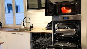 A modern kitchen with a dishwasher, oven, and microwave.