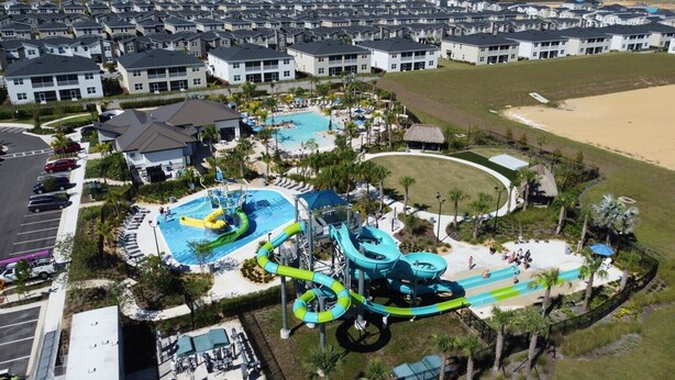 Un parc aquatique doté de plusieurs piscines et de toboggans, entouré d’immeubles d’habitation.