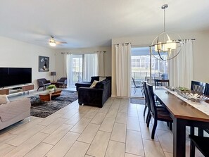Ein modernes Wohnzimmer mit Flachbildfernseher, Sofas, einem Esstisch und einer Deckenleuchte.