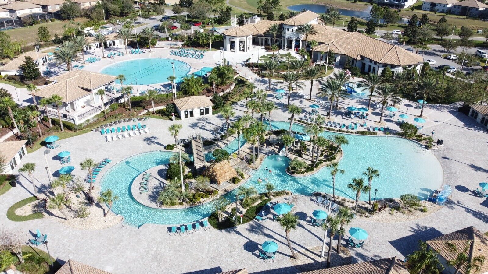 Un resort con varias piscinas, zonas de descanso y palmeras.