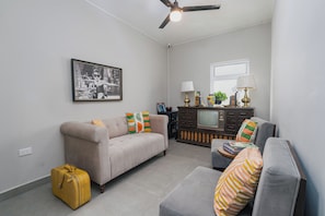 A living room with a sofa, armchair, and a television set against a wall.