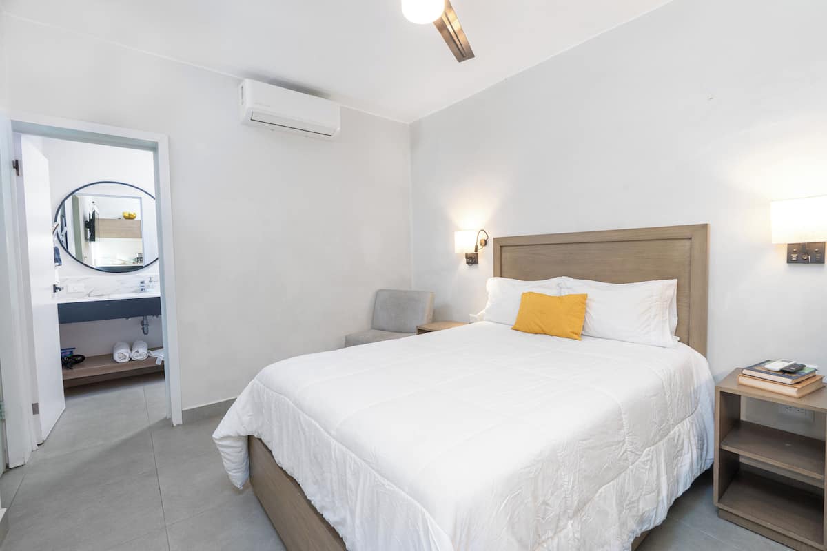 A bedroom with a bed, bedside tables, a nightstand, a mirror, and a wardrobe.