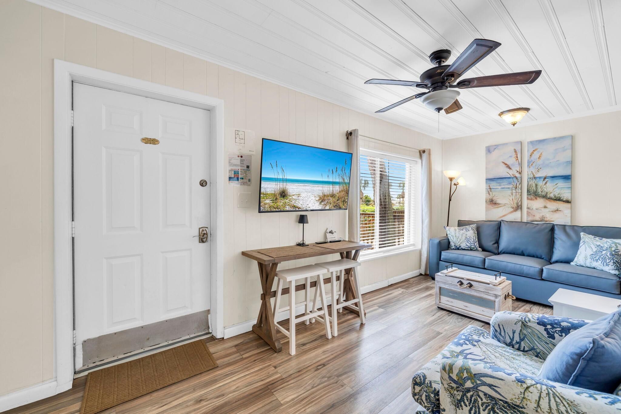 A living room with a television, a ceiling fan, a sofa, a coffee table, and a wooden bench.