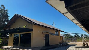 Un edificio de una planta con techo de tejas, un porche cubierto y un camino de entrada pavimentado.