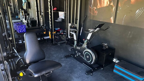 Een sportschool met trainingsapparatuur, een bank en een fiets aan de muur.
