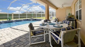 Et overdækket udendørsområde med pool, siddepladser og grill.