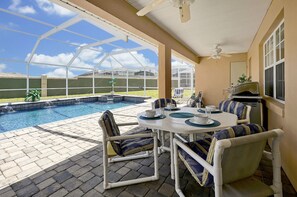 Ein überdachter Außenbereich mit Pool, Sitzgelegenheiten und Grill.