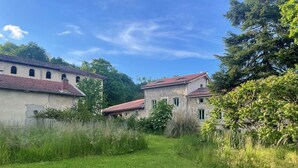En lantlig miljö med byggnader av sten, en gräsbevuxen stig och träd.