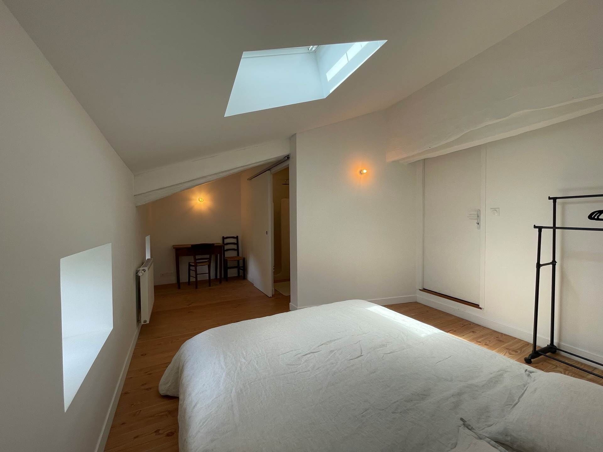 Ein Schlafzimmer mit Dachfenster, einem Bett, einem Schreibtisch mit Stuhl und einem Kleiderschrank.