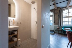 Un baño moderno con ducha, lavamanos y estantes.