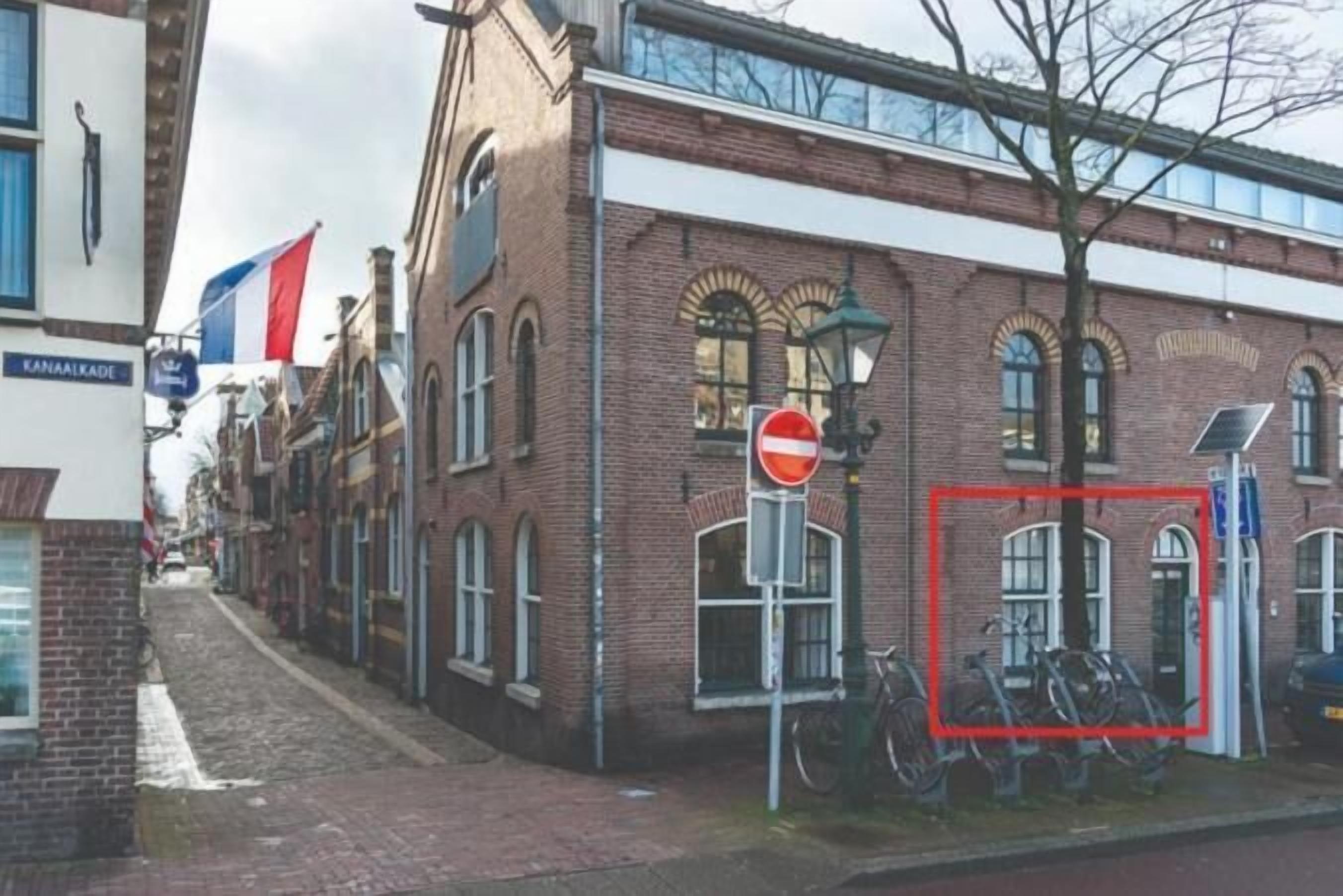 A narrow street with a no entry sign, a bicycle rack, and a building with a sign reading 'KANAALKADE'.
