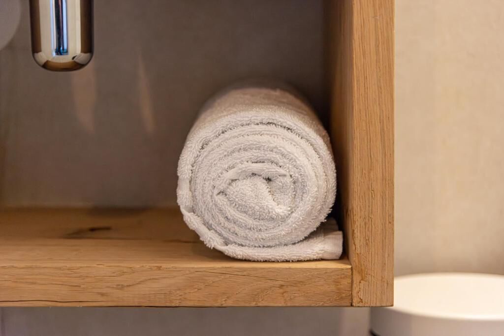 A wooden shelf with a rolled white towel.