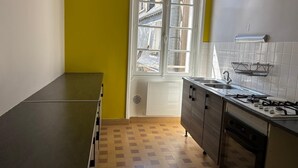 Keittiössä on ikkuna, pesuallas, liesi ja laatoitettu seinäosa tiskipöydän yläpuolella.