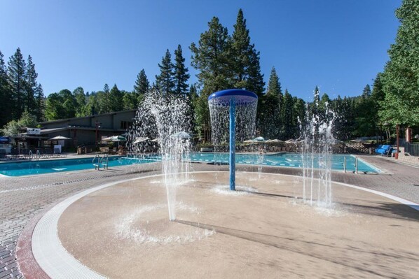 Ein Poolbereich mit einem zentralen Wasserspiel und umliegenden Liegestühlen.