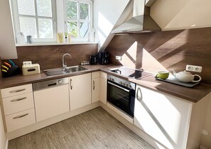 Une cuisine moderne équipée d’un lave-vaisselle, d’un four et d’une fenêtre donnant sur la verdure.