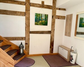 Et værelse med en trætrappe, et skovmotiv, et skab og en skraldespand.