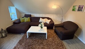 En moderne stue med en modulsofa, et hvidt sofabord og en dekorativ vase.