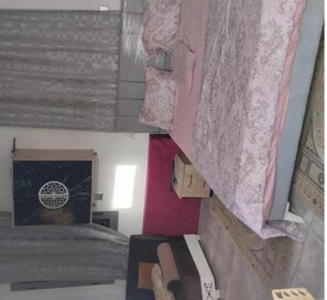 Quarto com colcha estampada, parede de destaque vermelha e painel decorativo na parede.