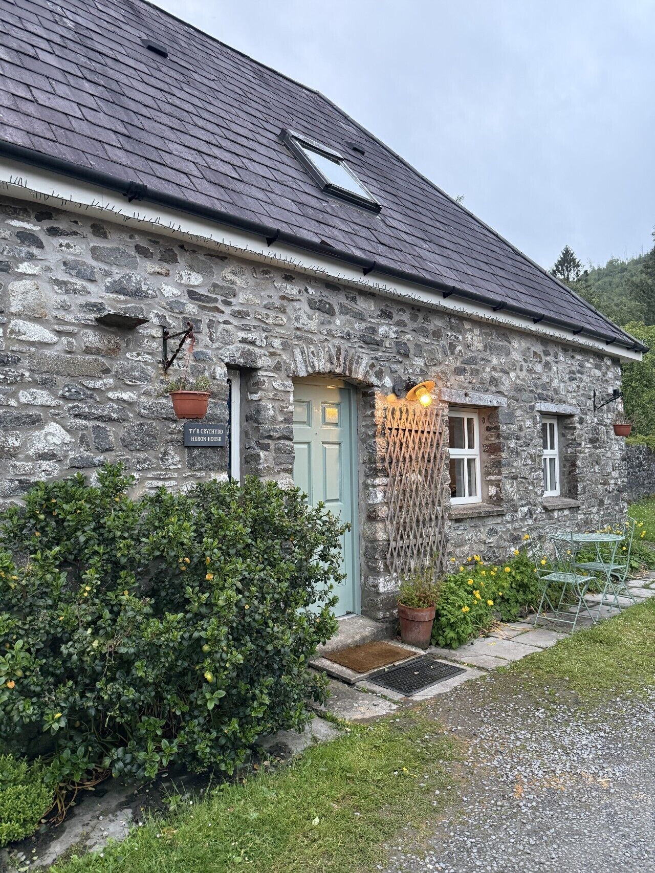 A stone house with a green door, a small porch, and a window.