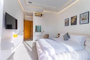 Une chambre moderne avec un grand lit, un tĂ©lĂ©viseur Ă Ă©cran plat, une table de chevet et une fenĂȘtre.
