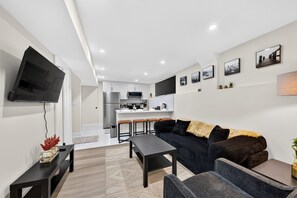 Un salon moderne avec un canapé, une table basse et un téléviseur fixé au mur.