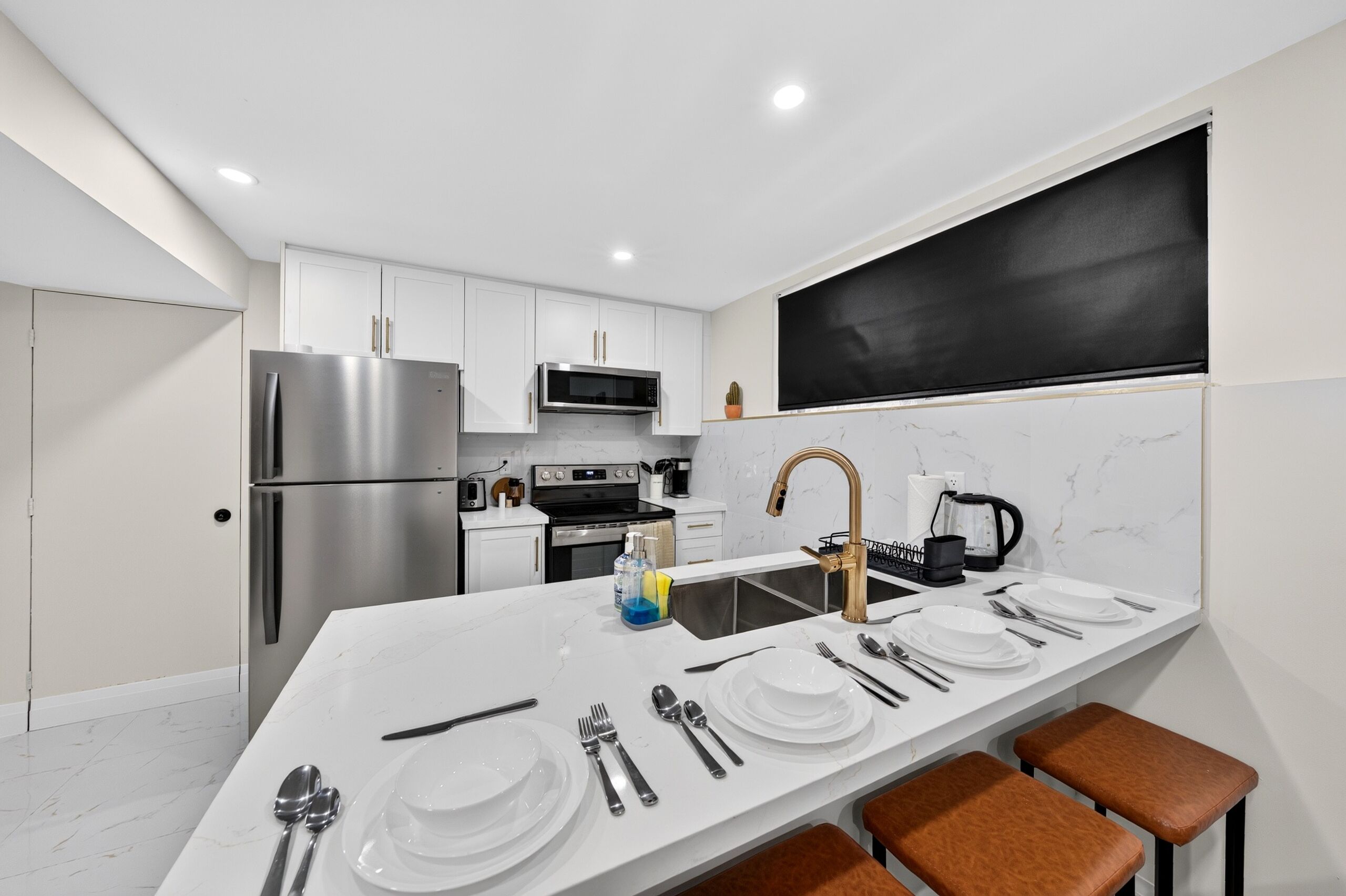 A modern kitchen with a central island, stainless steel appliances, and a blackboard on the wall.