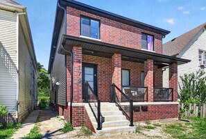 Une maison à deux étages, construite en briques, avec un porche à l’avant, un numéro « 9 » bien visible sur la porte et un petit jardin devant.