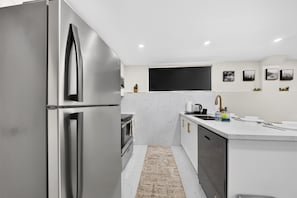 Una cucina moderna con forno integrato, frigorifero in acciaio inossidabile e zoccolo paraschizzi in marmo.
