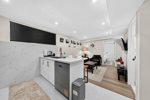 A modern kitchen with a central island, white cabinetry, and a built-in dishwasher. - Cozy Modern Walkerville
Basement Apartment (Windsor)