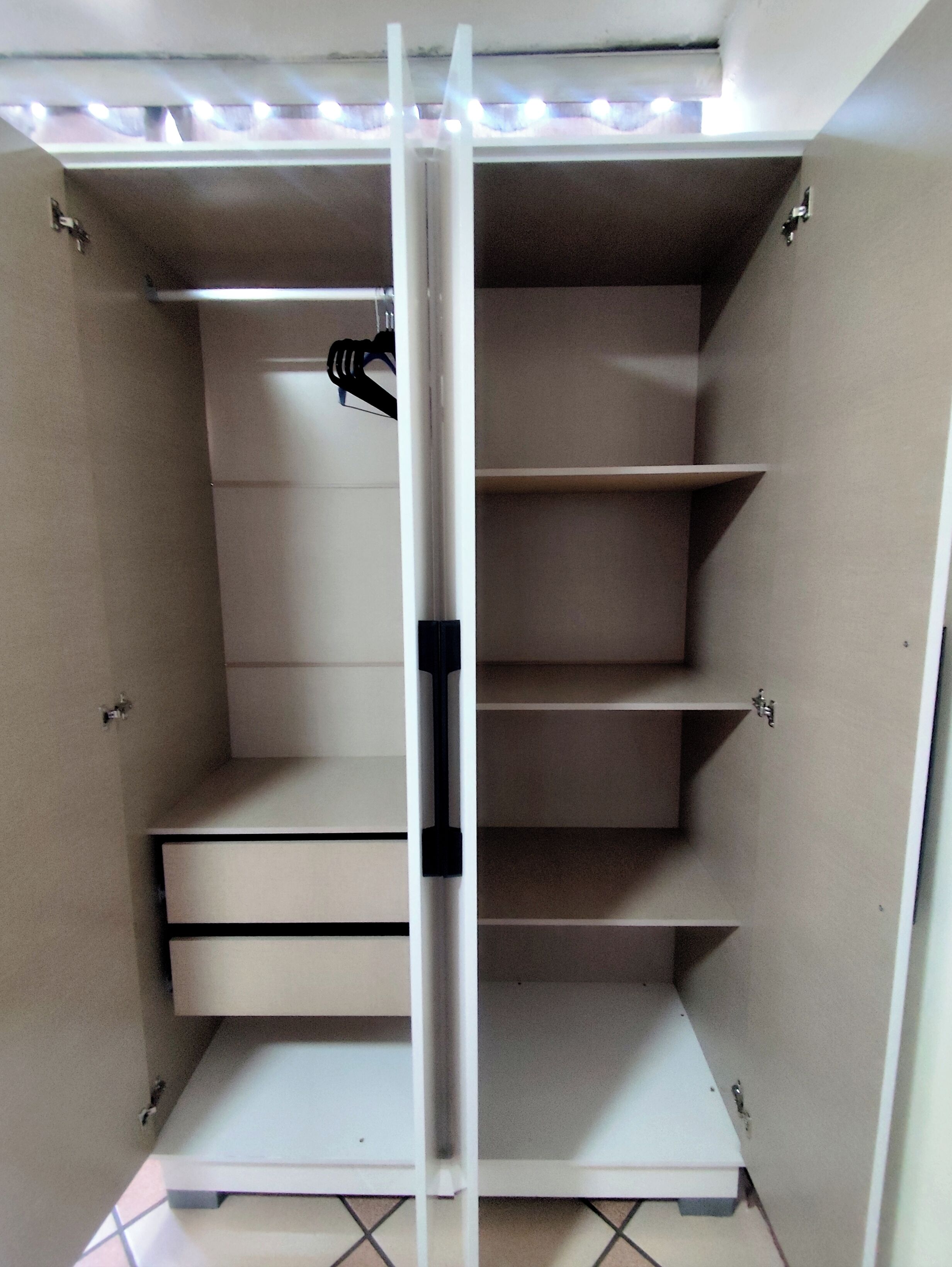 Een kast met verschillende planken en lades, voorzien van een lamp erboven.