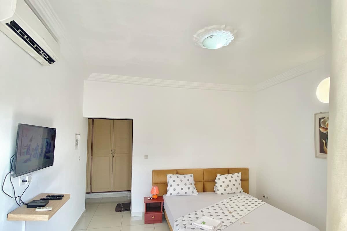 Une chambre dâhĂŽtel avec un lit, une tĂ©lĂ©vision, une petite table et une armoire.