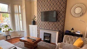 Una sala de estar con chimenea, televisor, sofá y una mesa de centro.