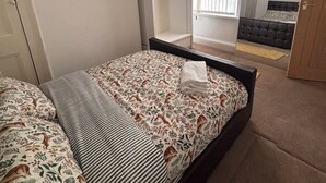 Un dormitorio con cama, armario, espejo y ventana con persianas.