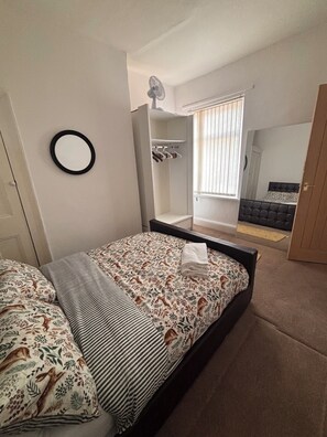A bedroom with a bed, a wardrobe, a mirror, and a window with blinds. - Spacious 4BR Home | Sleeps 7 | 2 Baths | Long Stays (Manchester)
