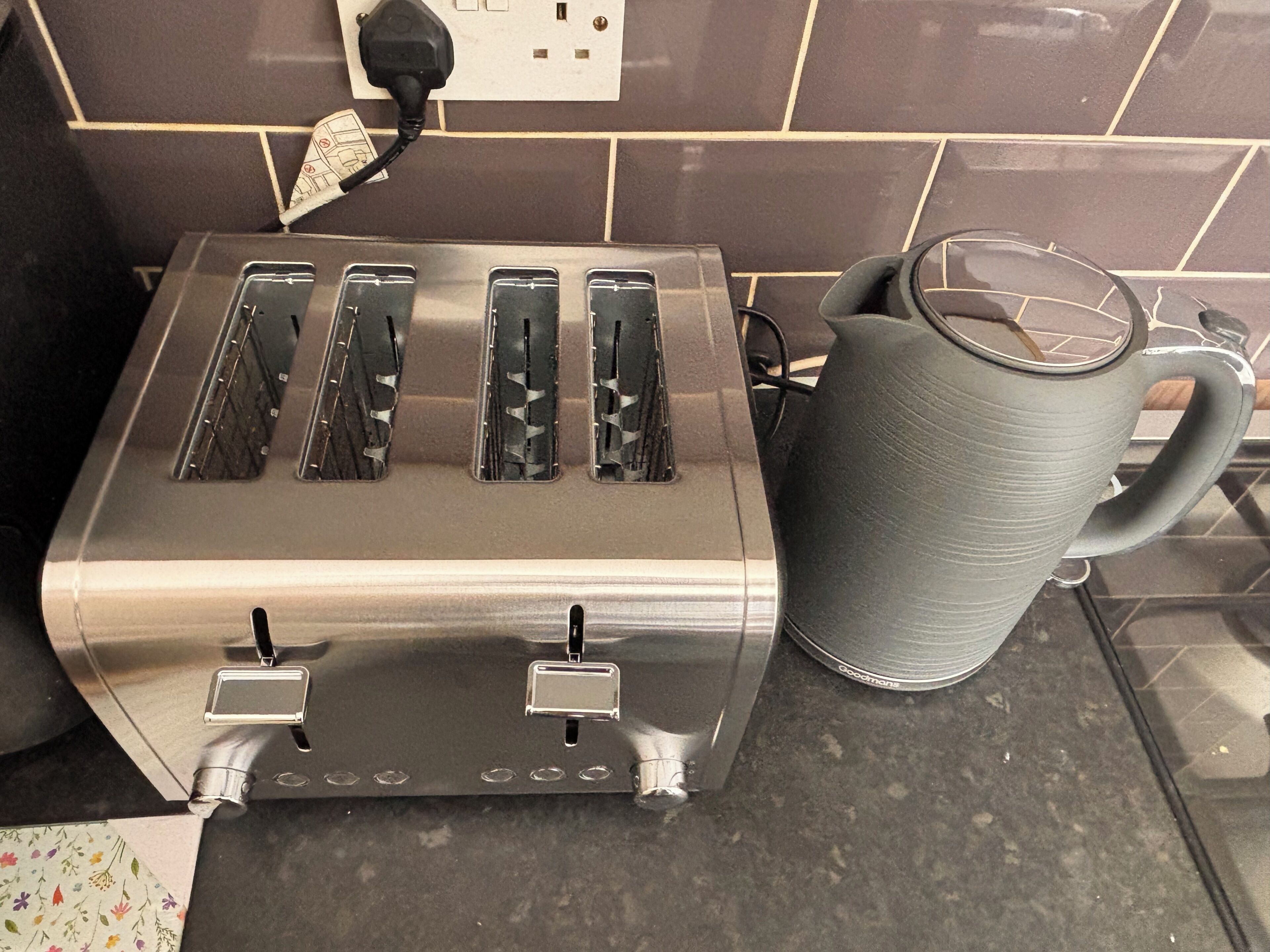 Una cucina con un tostapane in acciaio inox e una tazza grigia sul bancone.