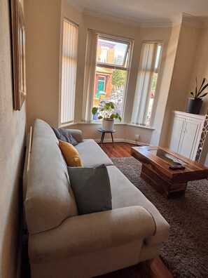 A living room with a sofa, a coffee table, and a potted plant. - Spacious 4BR Home | Sleeps 7 | 2 Baths | Long Stays (Manchester)