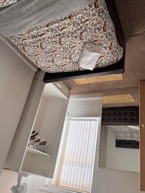 A room with a bed, a window with blinds, a ceiling fan, and a mirror. - Spacious 4BR Home | Sleeps 7 | 2 Baths | Long Stays (Manchester)